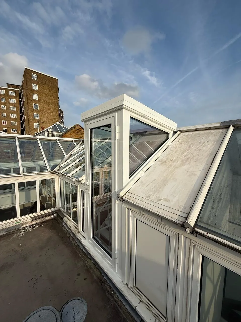 Glazed roof access structure on a city roof terrace