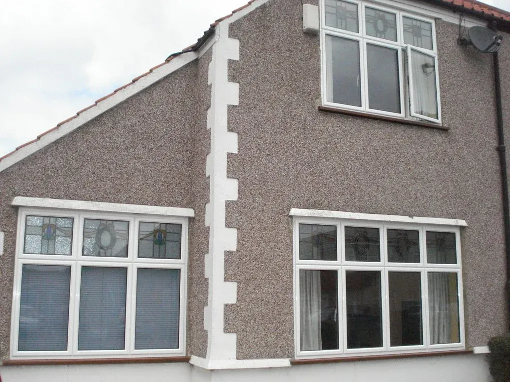 White uPVC windows on a pebble-dashed house